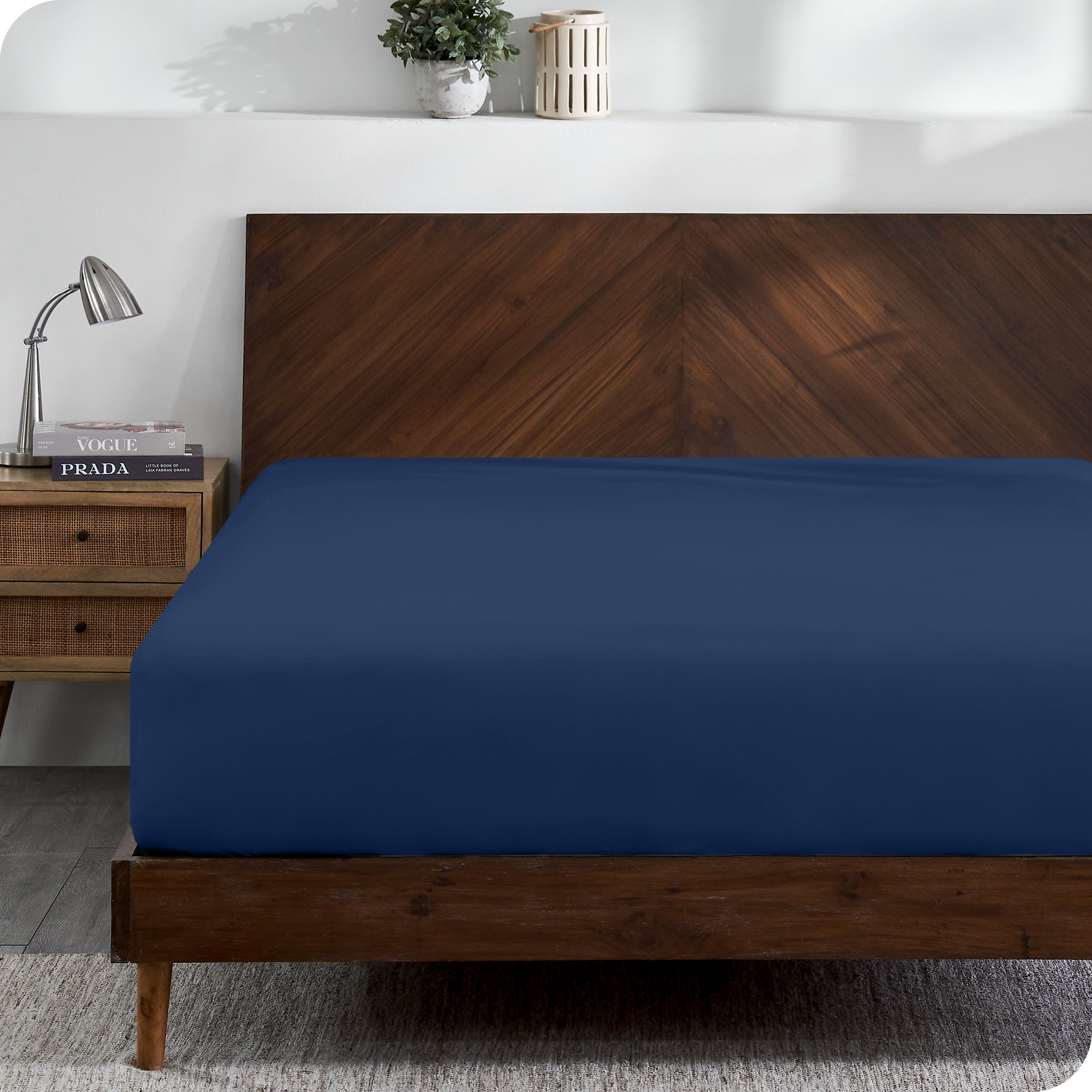 A modern wooden bed frame with a fitted sheet on the mattress