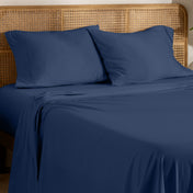 Organic jersey bed sheets and pillows on a bed with a wicker headboard.