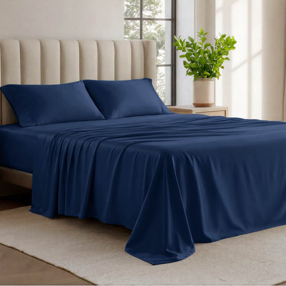 Organic cotton jersey sheets on a bed with a wicker headboard in a room with plants and a lamp.