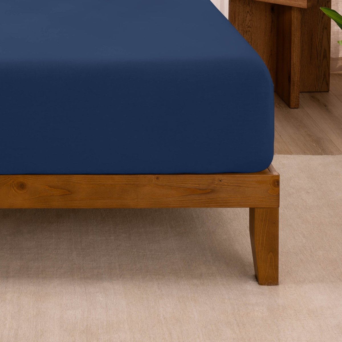 Fitted sheet on a wooden bed frame with a neutral background