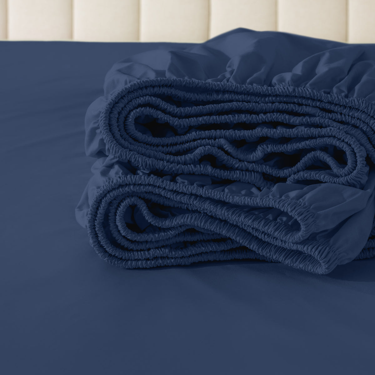 Folded fitted sheet on a bed with a neutral background