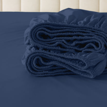 Folded fitted sheet on a bed with a neutral background