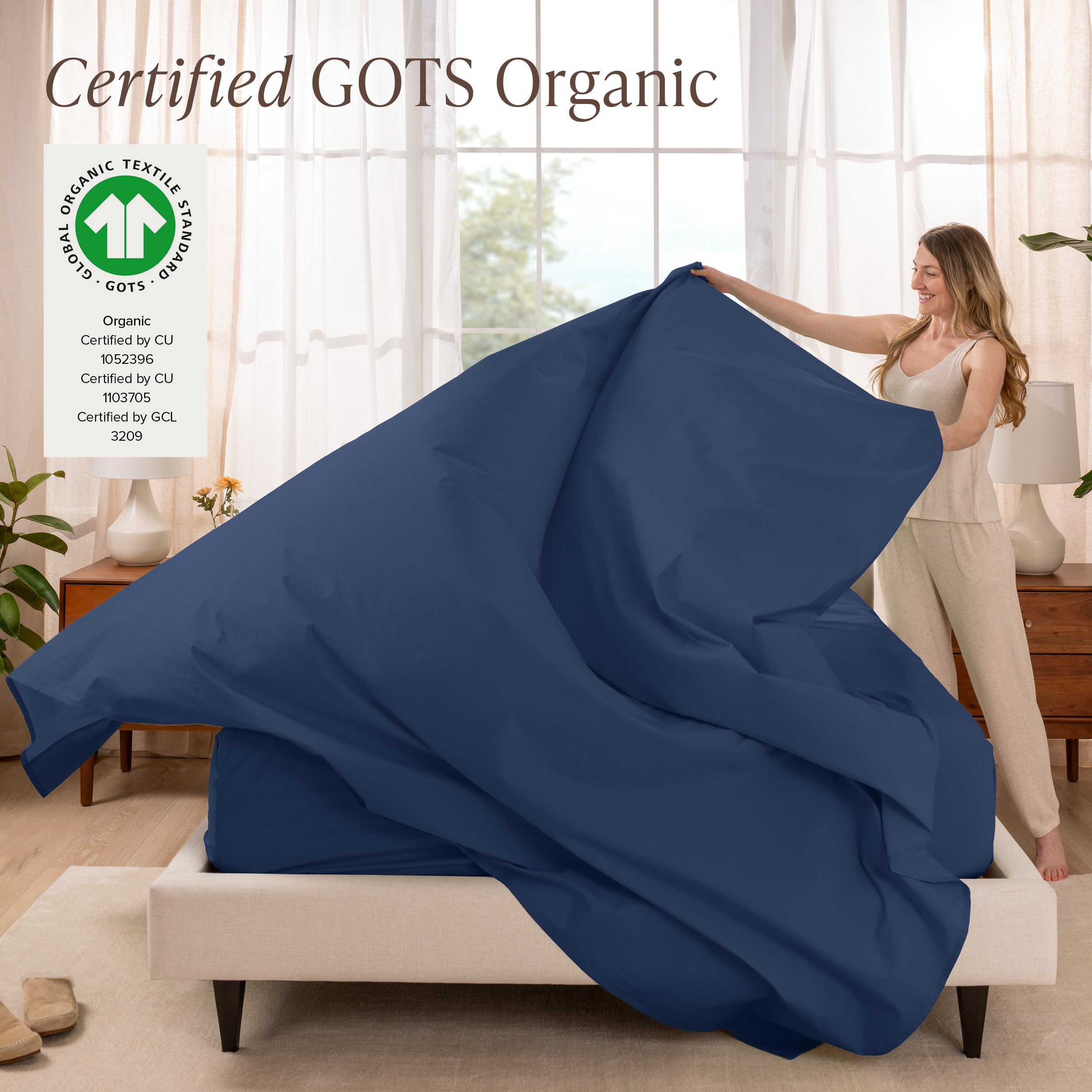 A woman is making a bed with organic cotton percale sheets