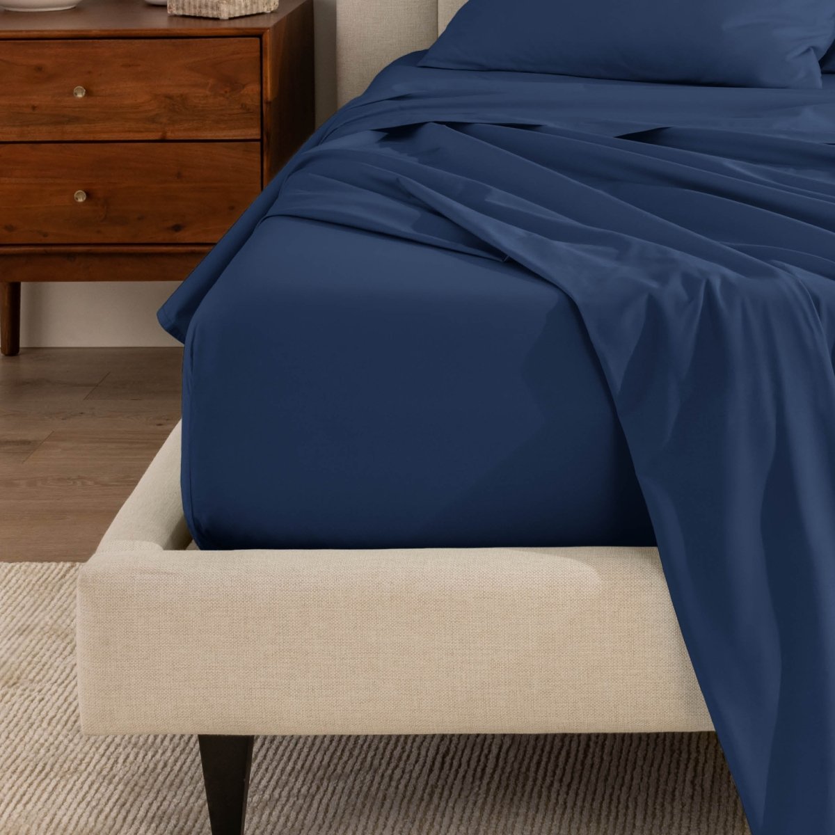 Top sheet and a matching fitted sheet on a bed with a beige bed frame