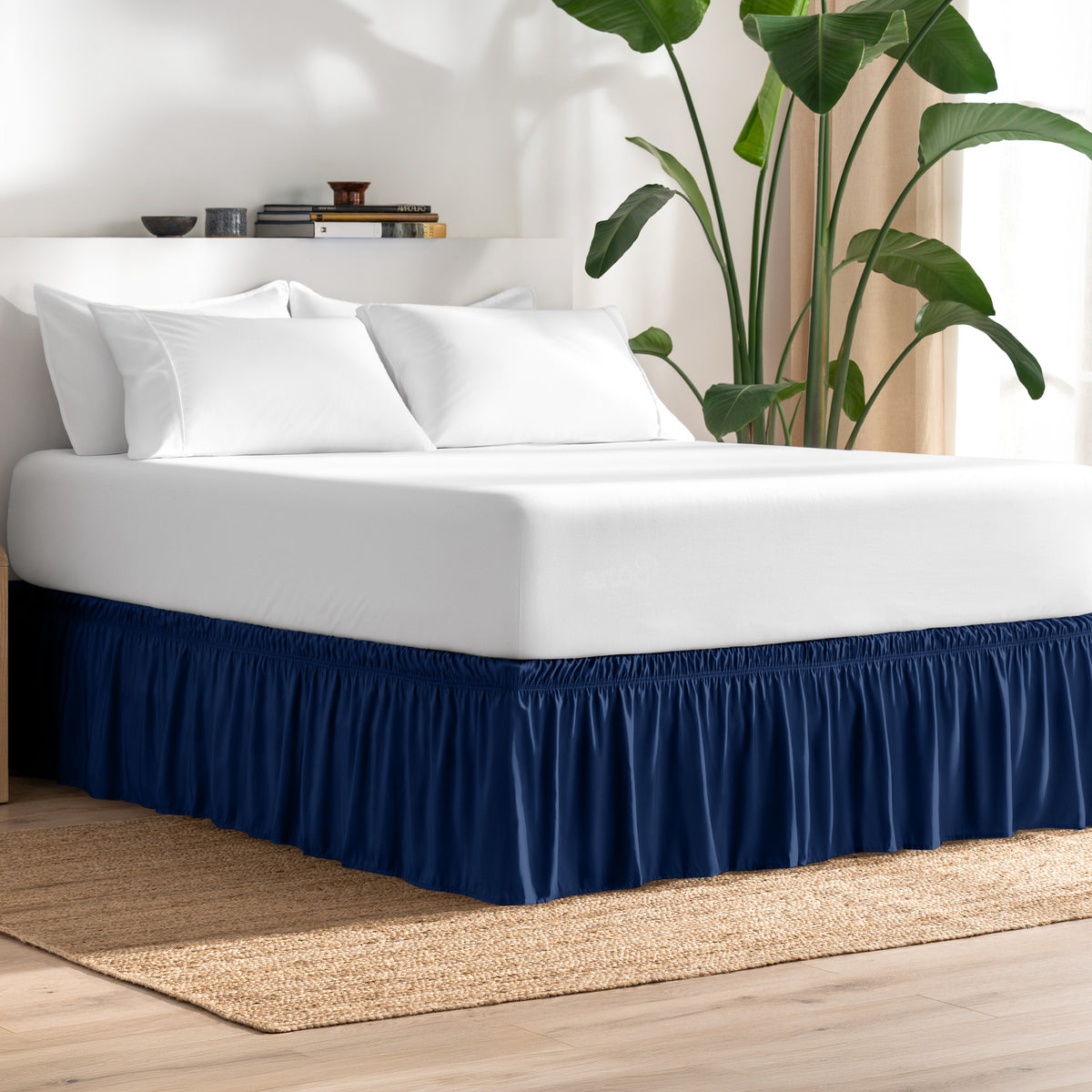 Bed with bed skirt, white bedding, and a plant in a room.