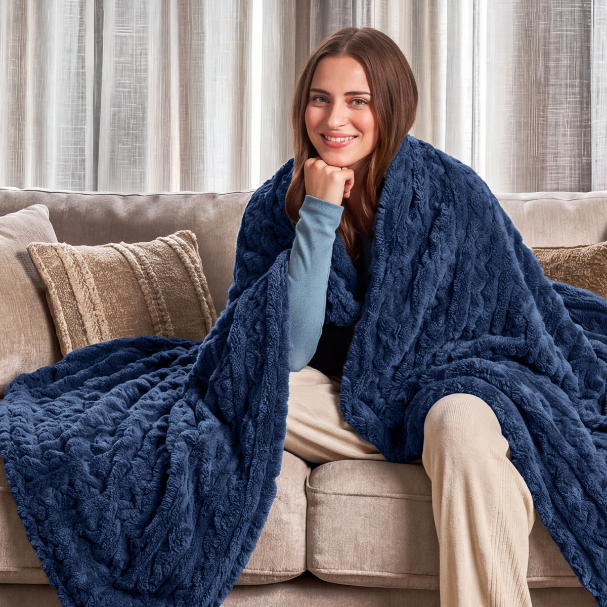 Woman sitting on a couch wrapped in a blue blanket in a cozy living room.
