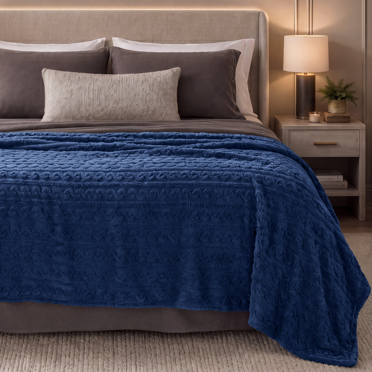 Bed with blue textured blanket in a bedroom setting.