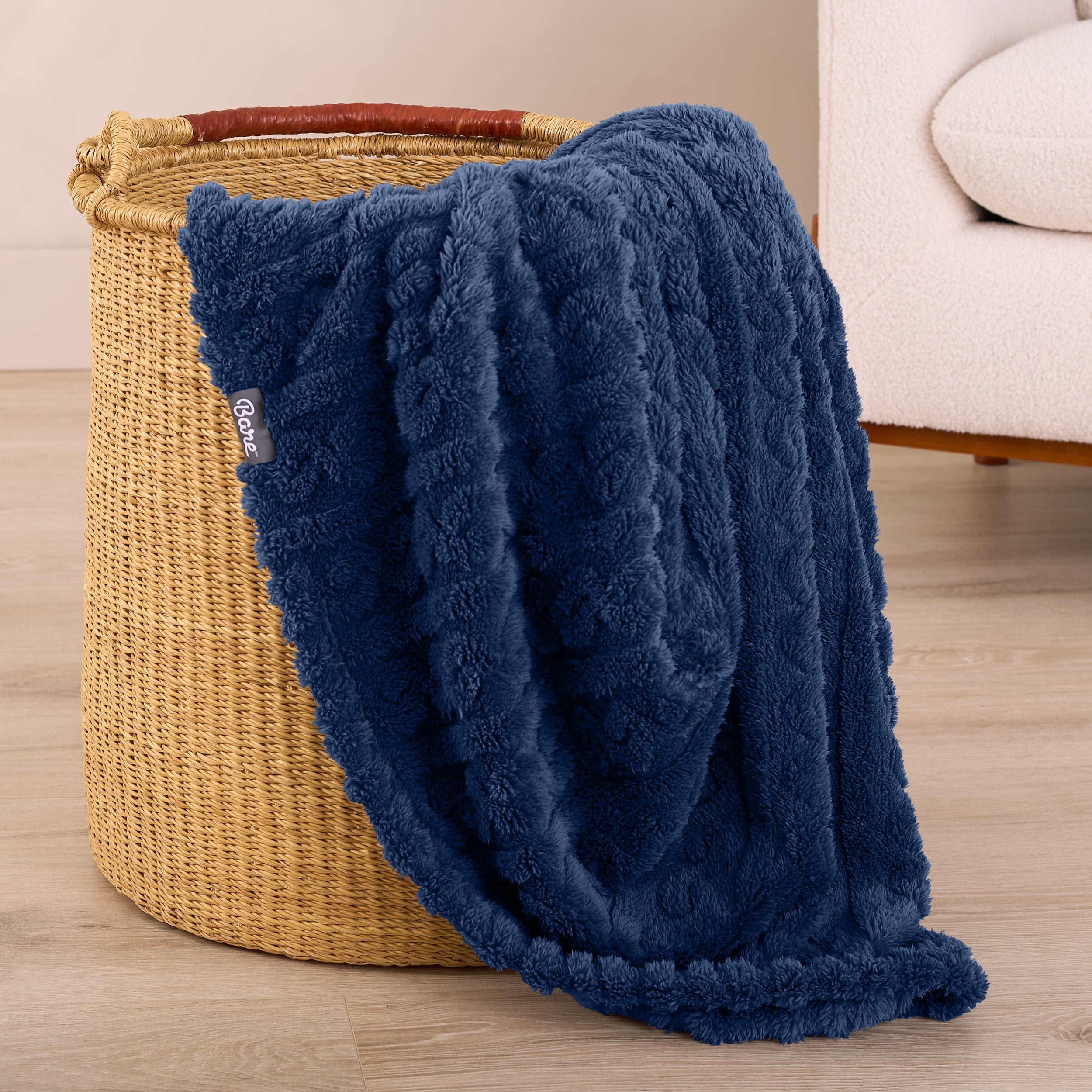A sherpa blanket is hanging over the edge of a woven hamper