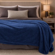 Bed with blue blanket and brown pillows in a bedroom setting