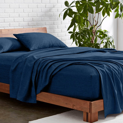 Microfiber sheet set on a wooden bed with a plant in the background