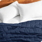 Close up of a weighted blanket on a bed next to pillows