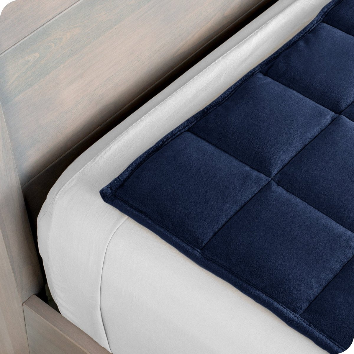 Close up of a weighted blanket on top of a bed made with white sheets