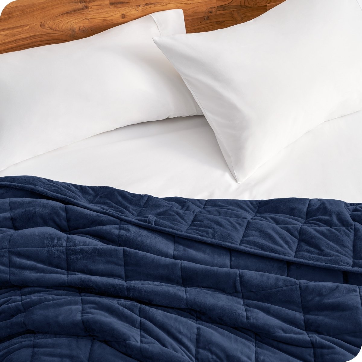 Close up of a weighted blanket on a bed next to pillows