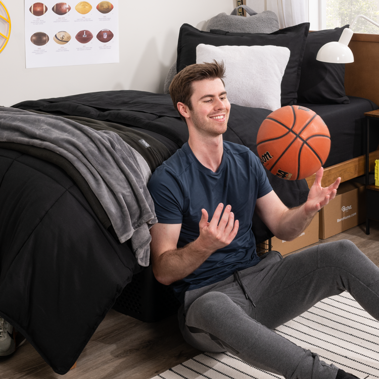 Young man throwing up basketball in dorm  room 
