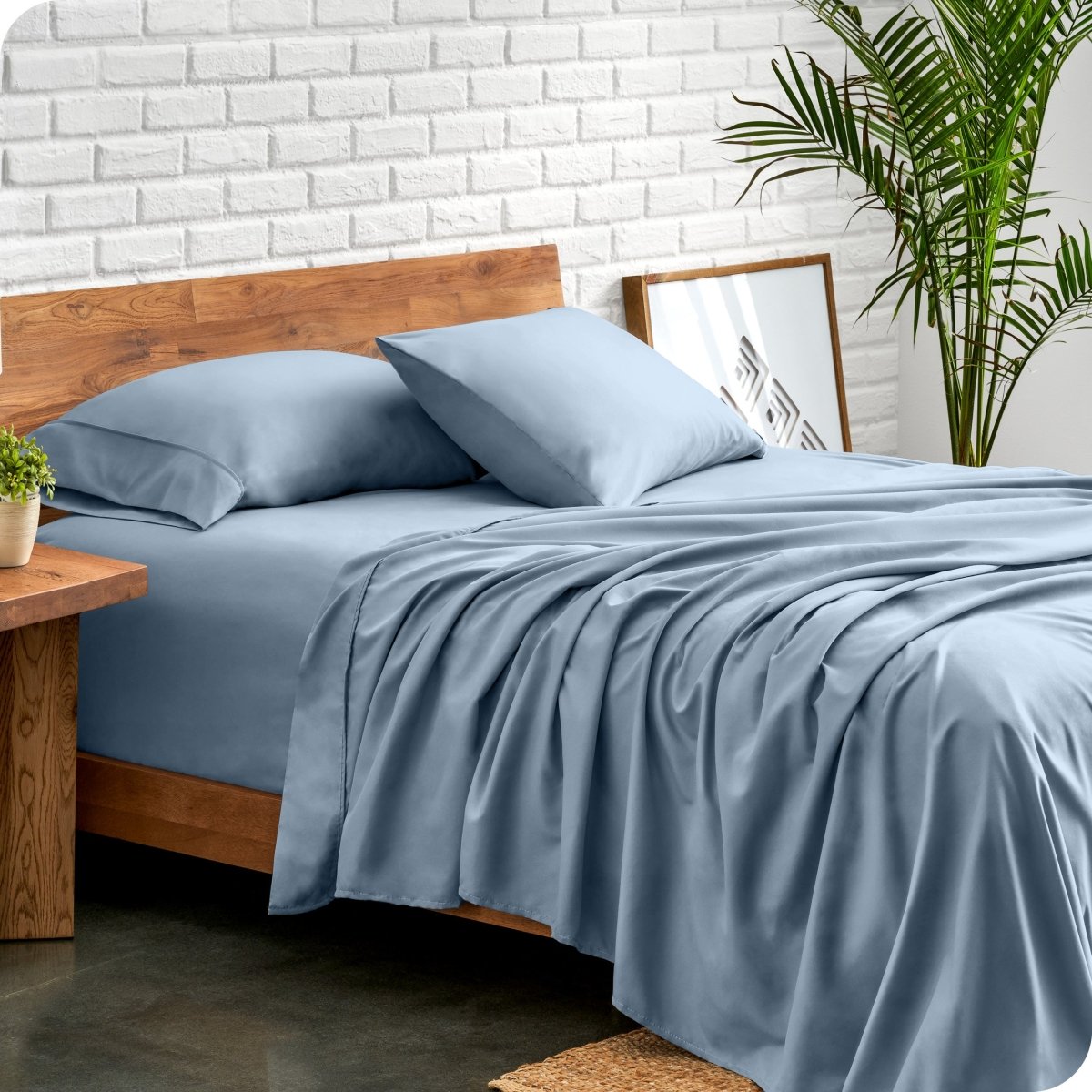 Bed with microfiber sheets against a white brick wall