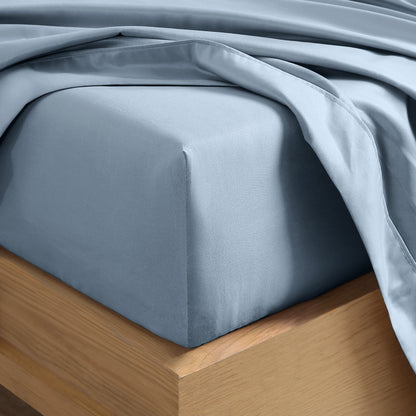 Close up of the corner of a mattress with a fitted sheet and flat sheet on it