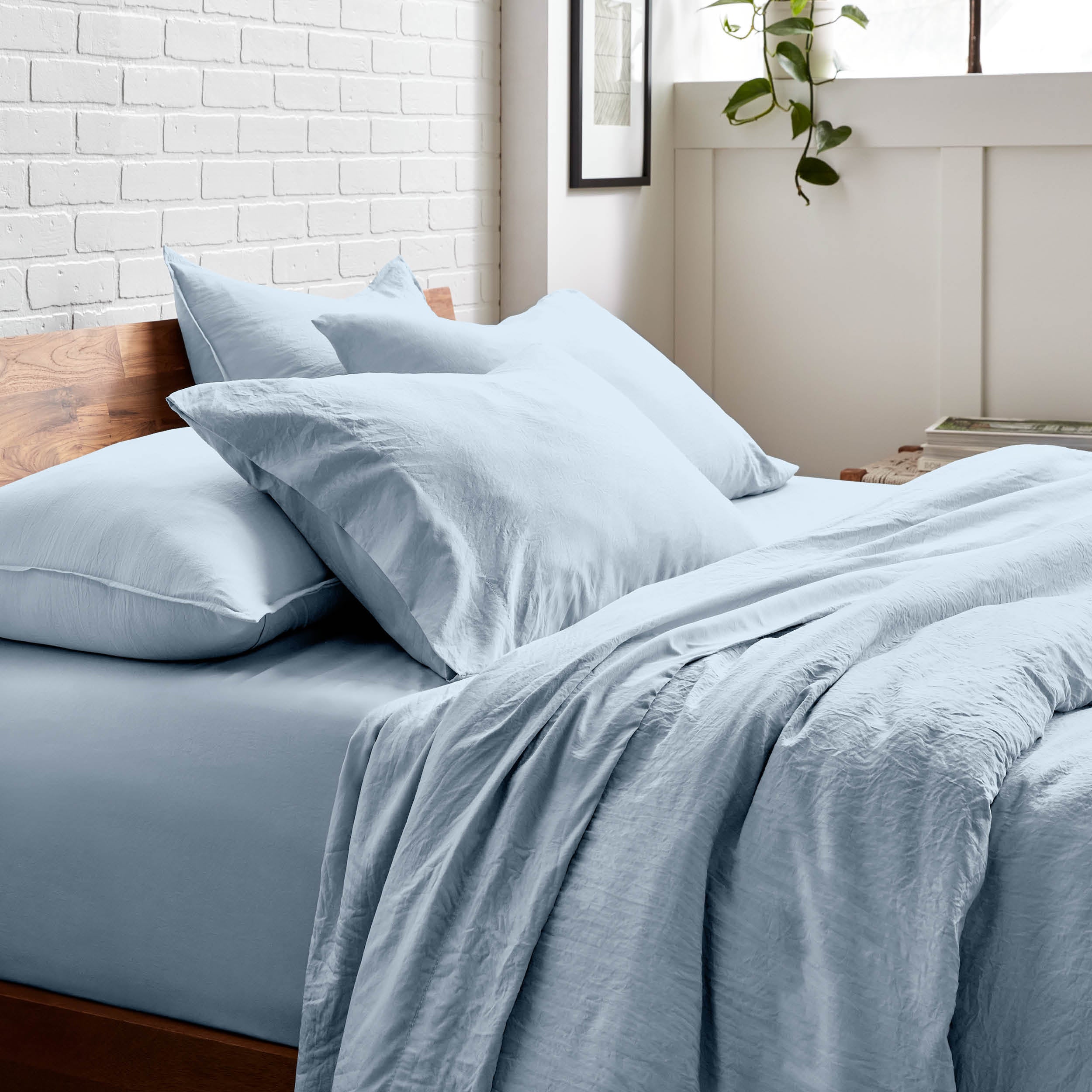 Bedding set on a bed with a white brick wall and window in the background