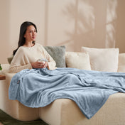 A woman sitting on a couch with a microplush blanket on her lap