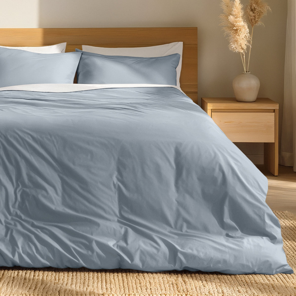 Percale bedding set on a bed with a wooden headboard and nightstand in a bedroom setting.