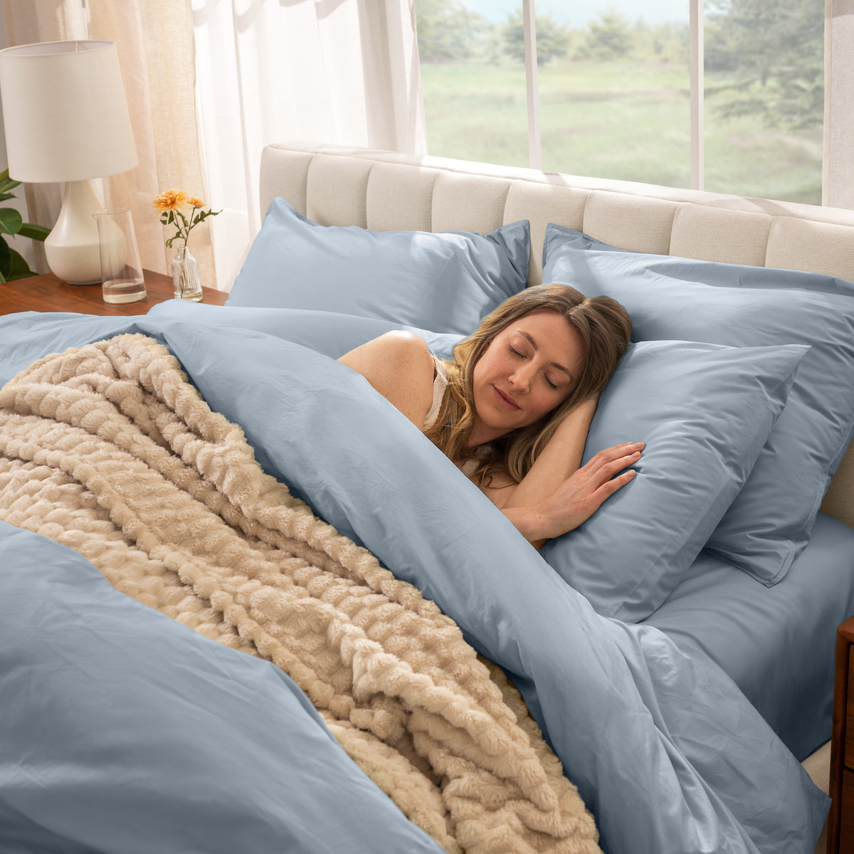 Woman sleeping in a bed with percale bedding and beige blanket