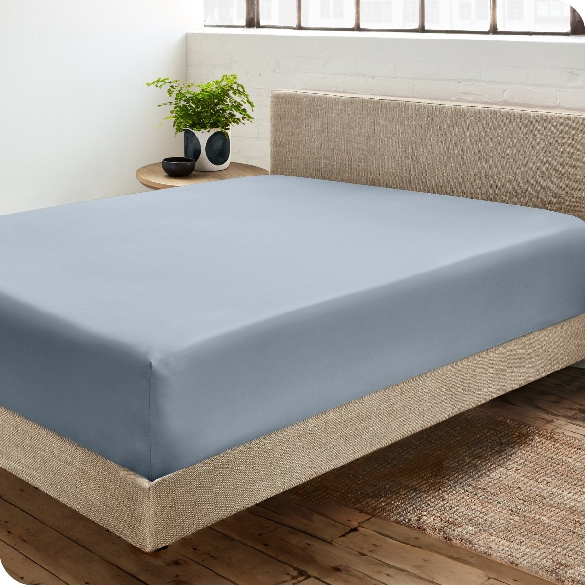 Diagonal view of modern bedroom with a sateen fitted sheet on the bed