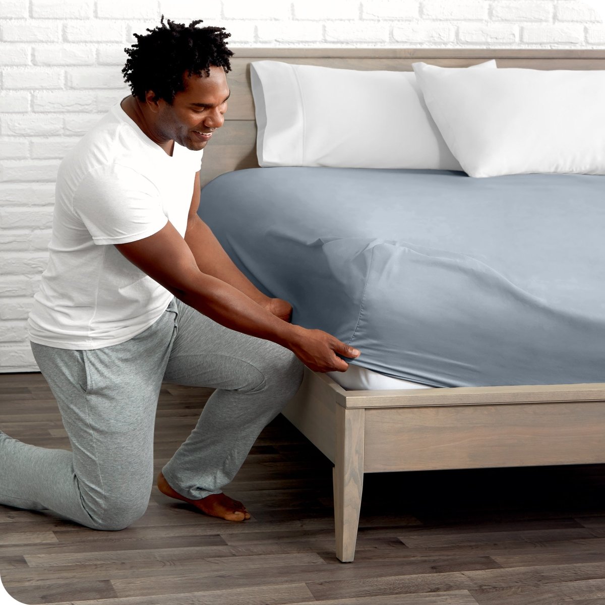 Man putting the corner of fitted sheet on a mattress