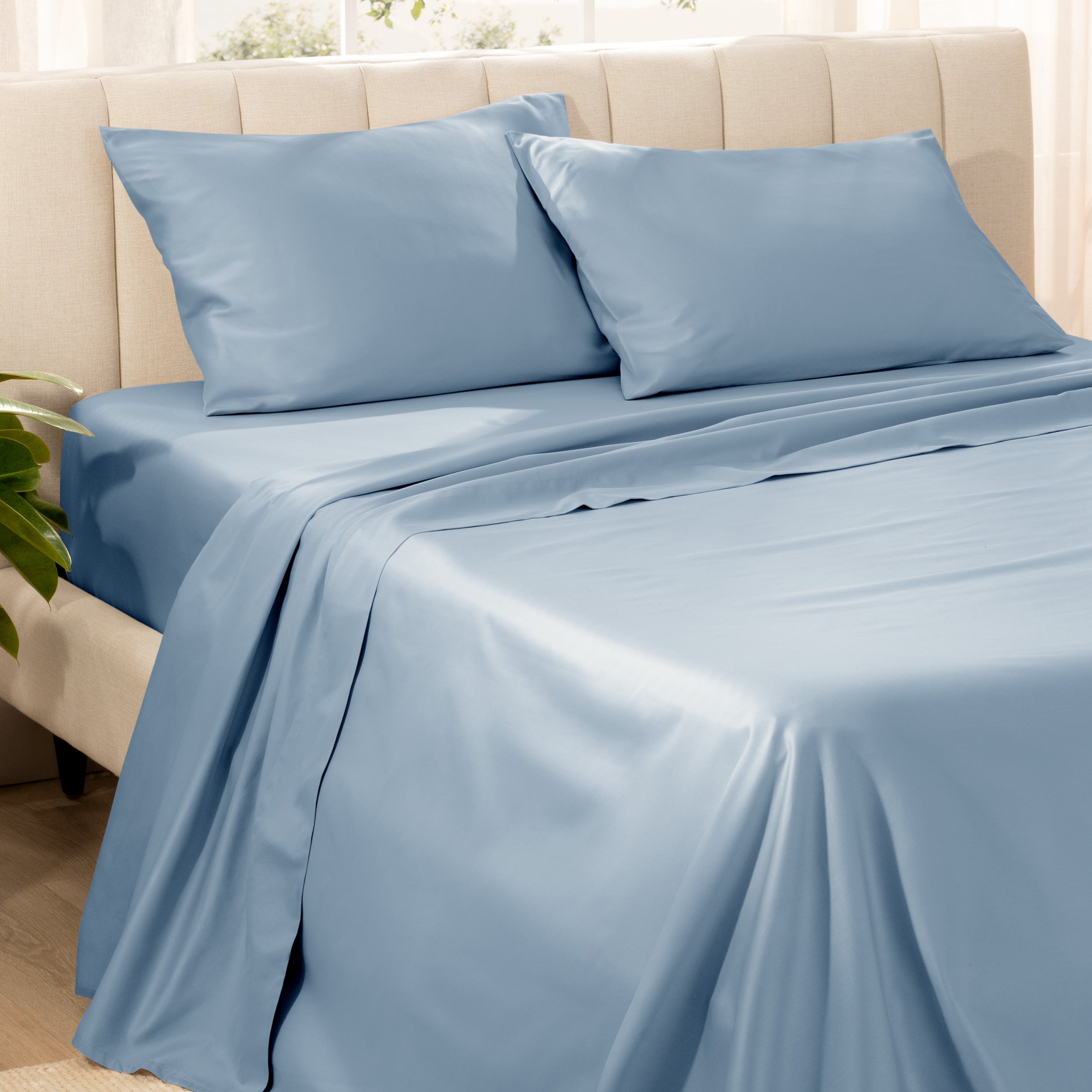 Bedding set on a bed with pillows in a bright room.