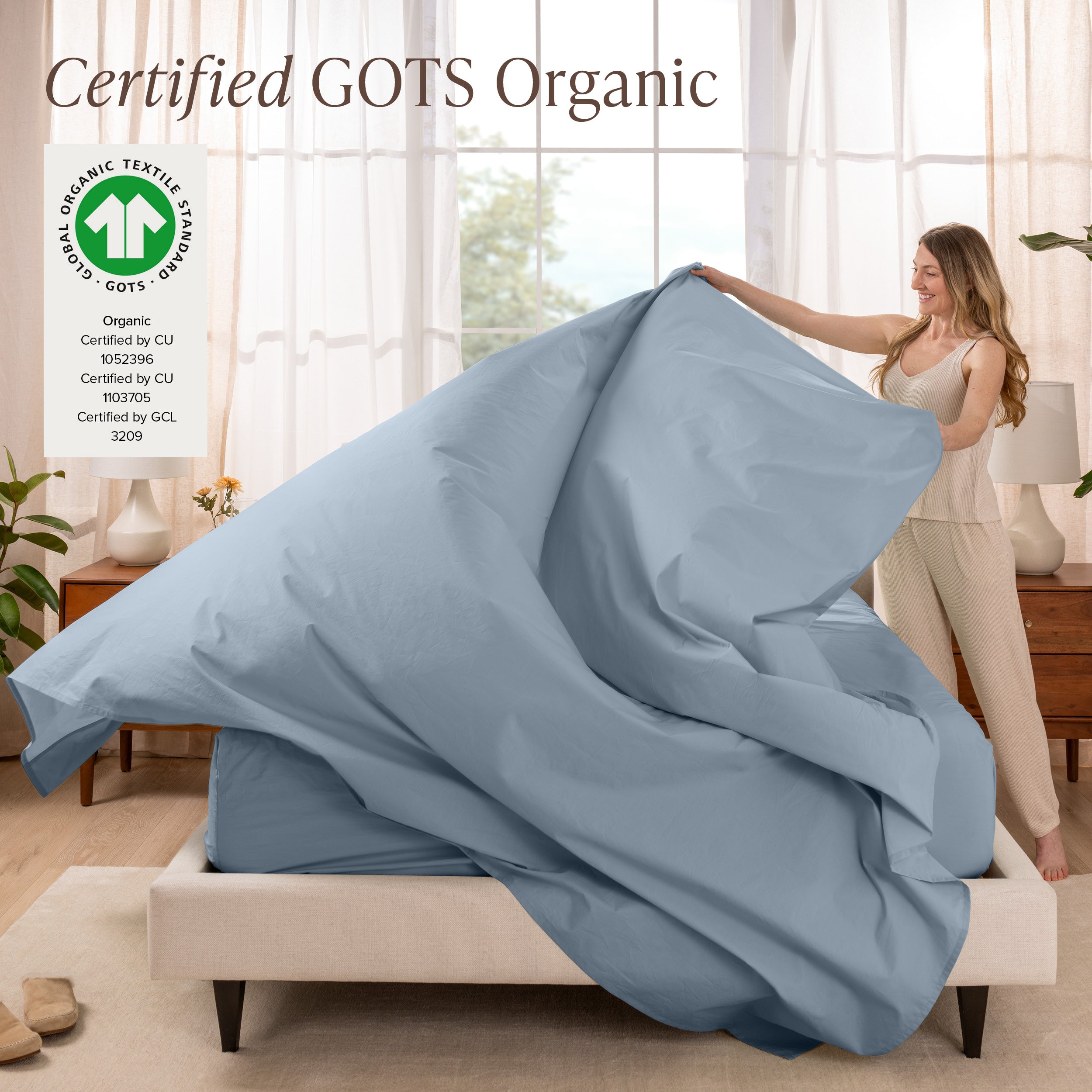 A woman is making a bed with organic cotton percale sheets