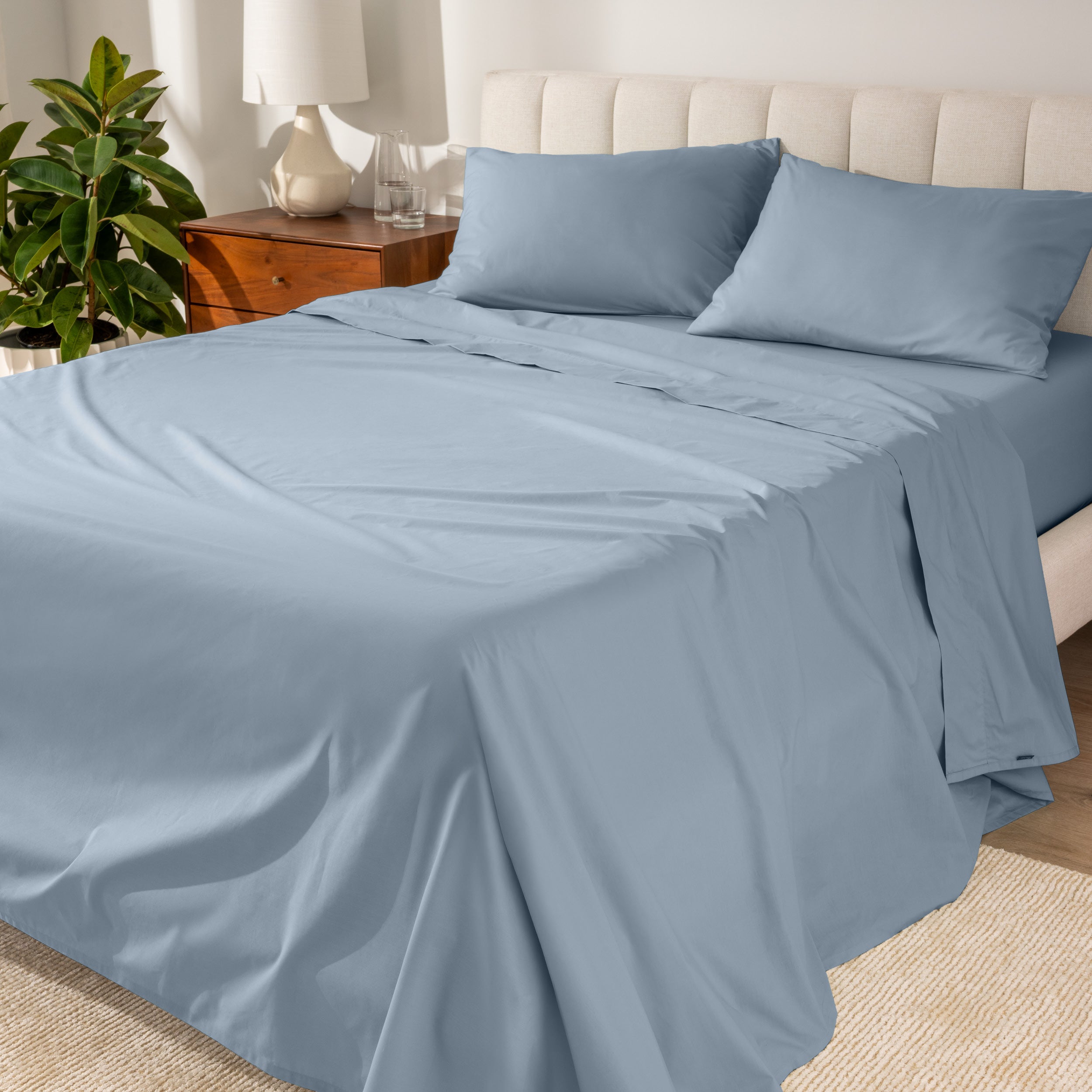 Percale sheets on a bed with a cream colored frame and headboard