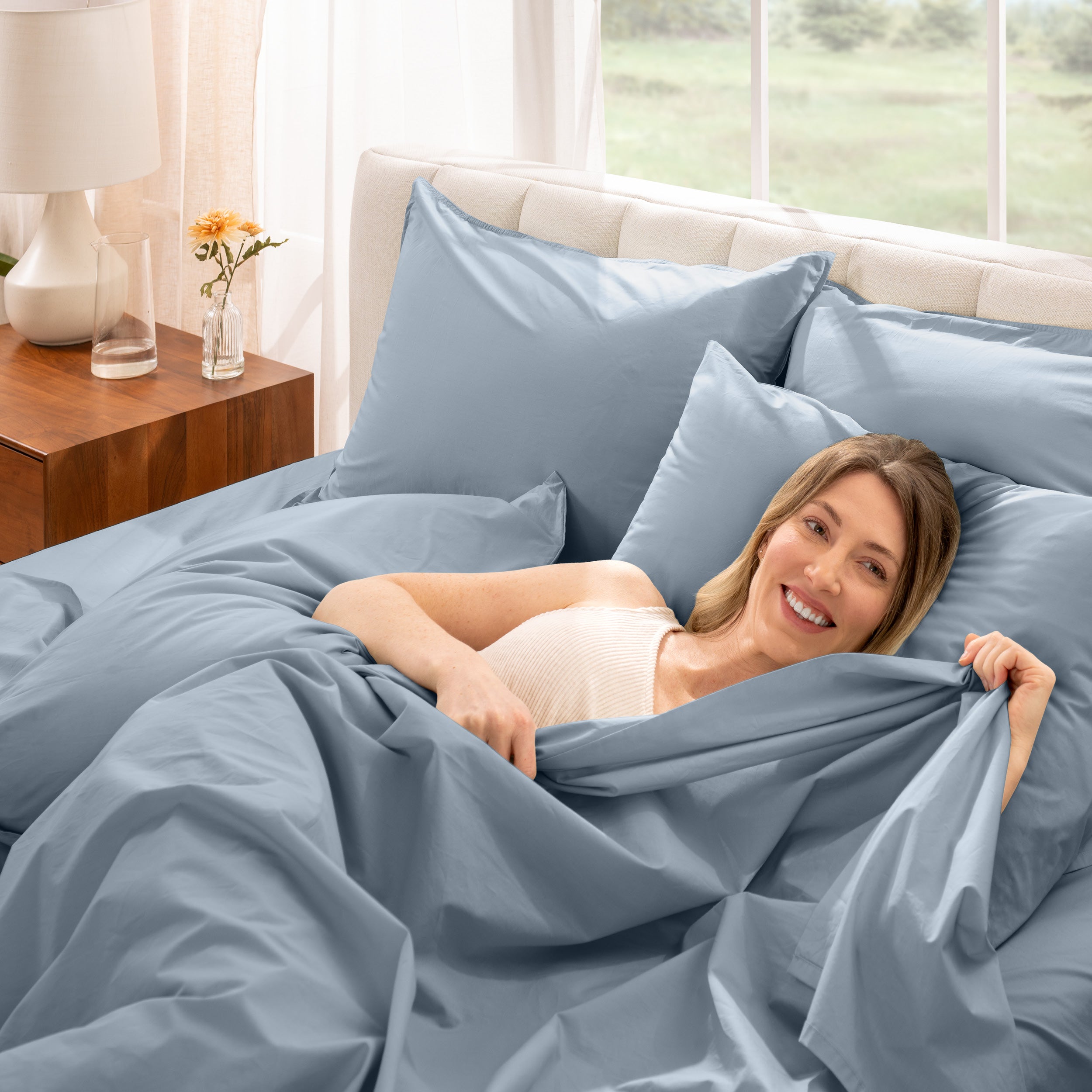 A woman is lying on a bed make with percale sheets and pillowcases