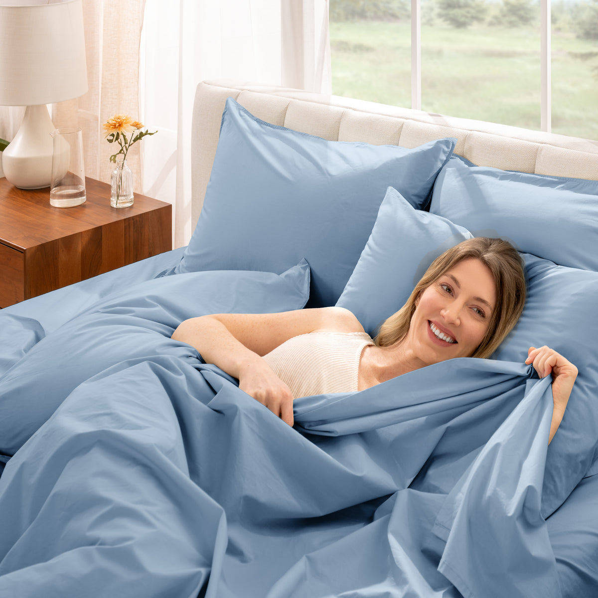 Woman lying in bed with percale bedding in a bright bedroom