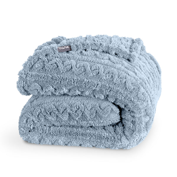 Folded blue blanket with a Bare brand tag on a white background