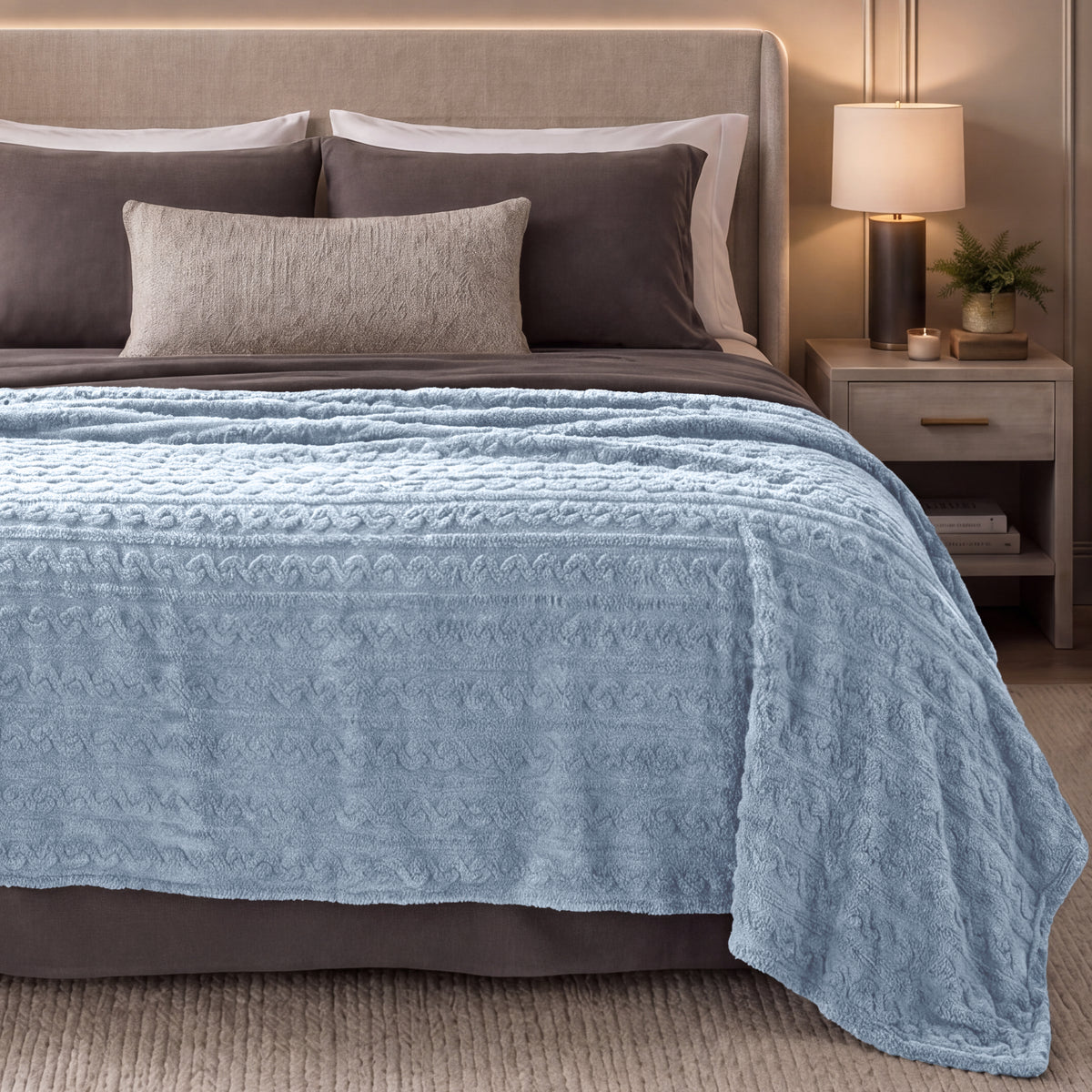 Bed with blue textured blanket in a bedroom setting.