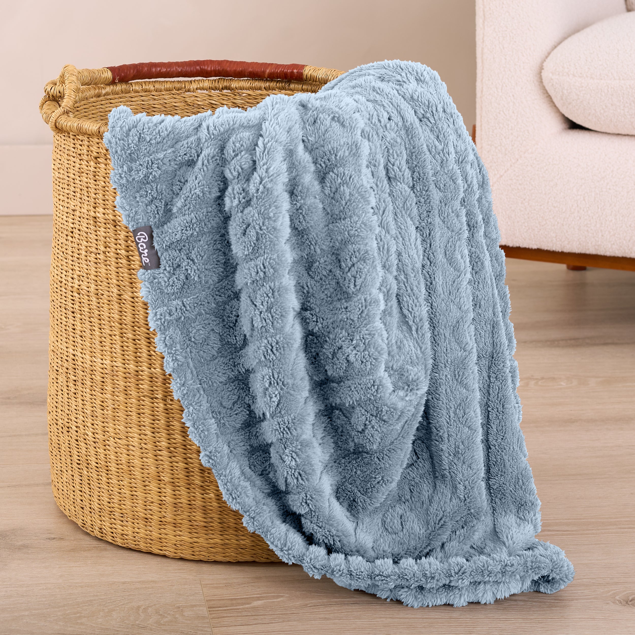 A sherpa blanket is hanging over the edge of a woven hamper