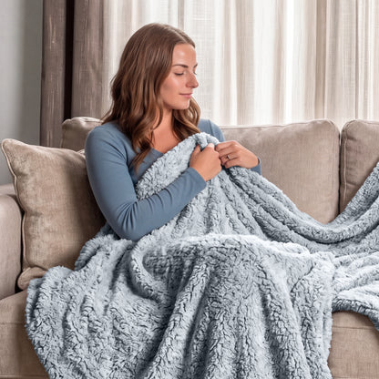Woman sitting on a couch wrapped in a fluffy textured blanket