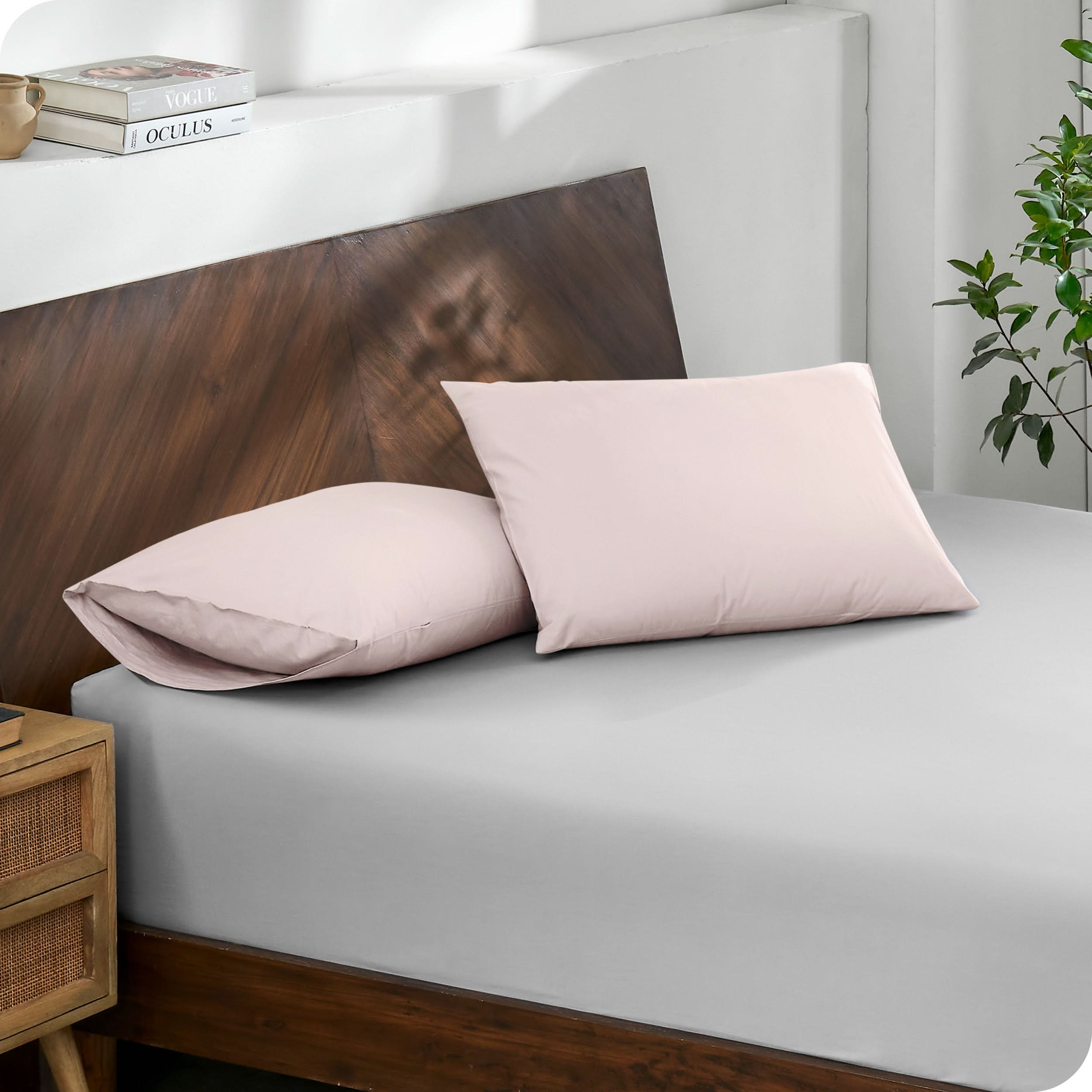 Diagonal view of modern wood bed with a fitted sheet and pillowcases