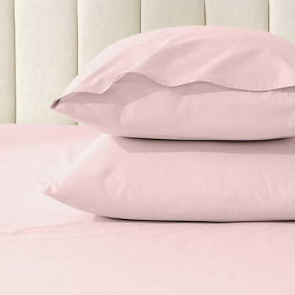 Two pillows stacked on a bed with percale pillowcases on them