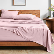 Bed with washed sheets and wooden headboard in a room setting.