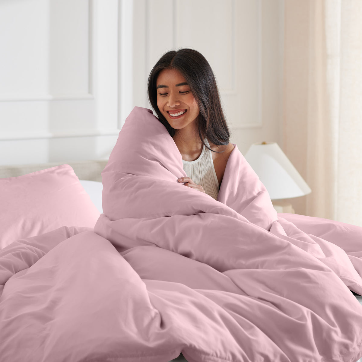 Woman smiling under duvet cover set in a bedroom setting