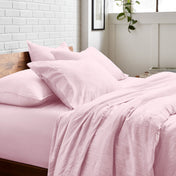 Bedding set on a bed with a white brick wall and window in the background