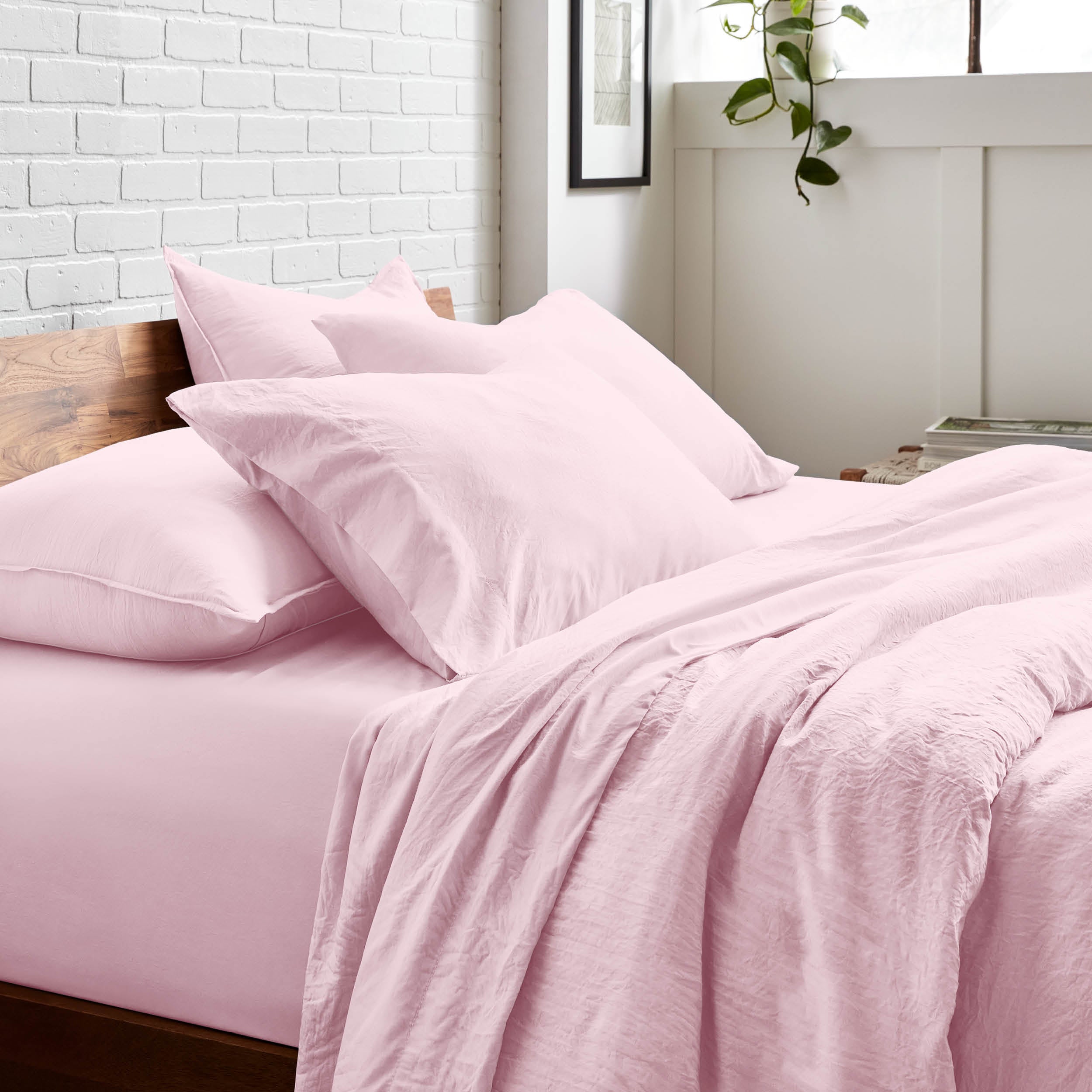 Bedding set on a bed with a white brick wall and window in the background