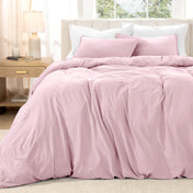 Bed with washed bedding and white pillows in a bright room