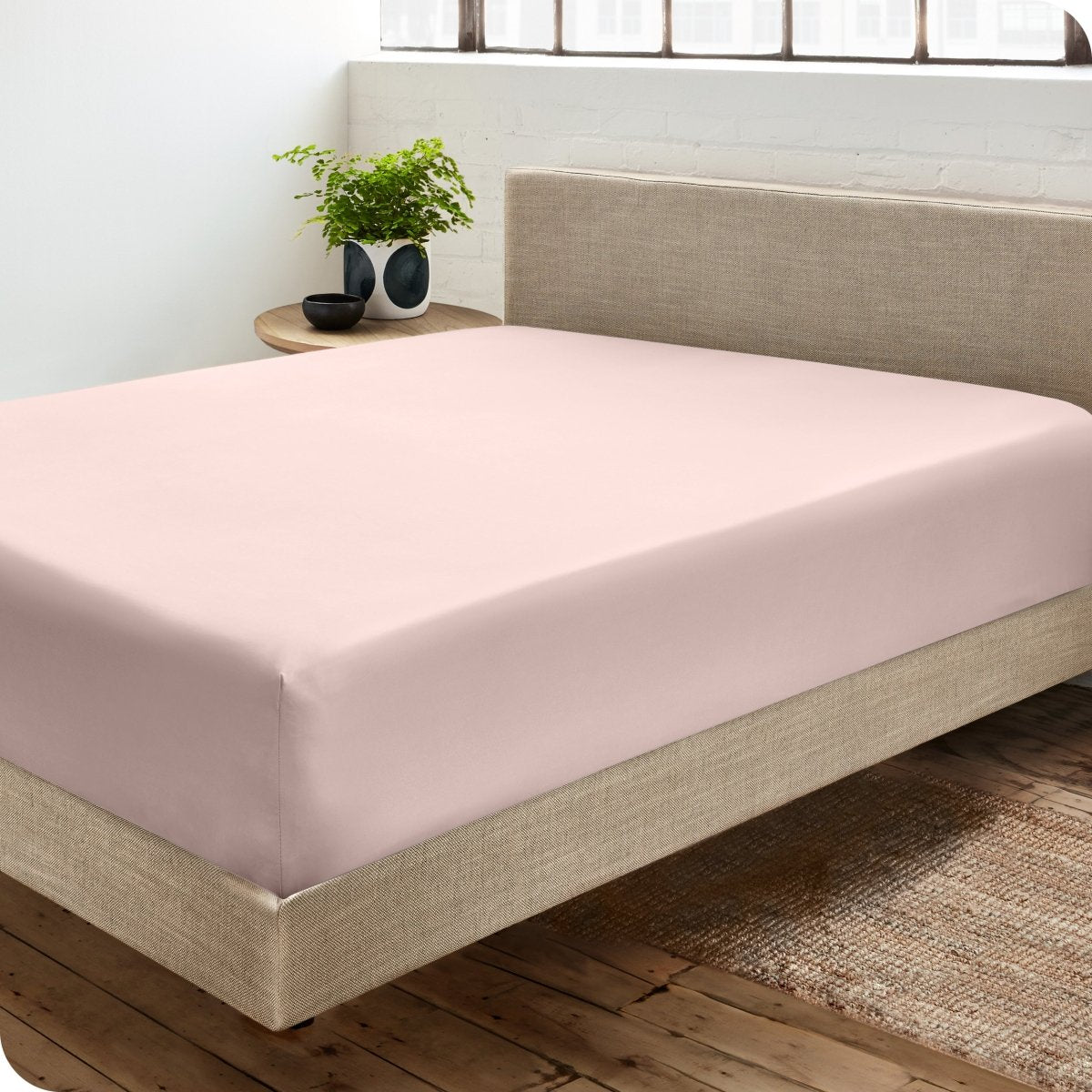 Diagonal view of modern bedroom with a sateen fitted sheet on the bed