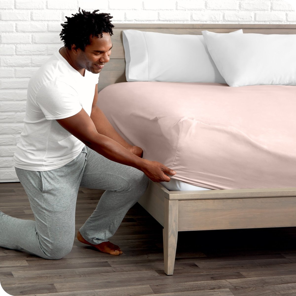 Man putting the corner of fitted sheet on a mattress