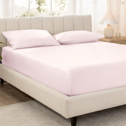 Bed with fitted sheet and pillowcases in a bright room.