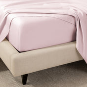 A close-up of the corner of a bed with a fitted sheet and matching flat sheet.