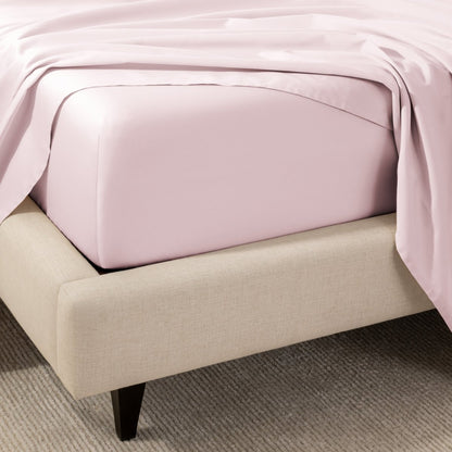 A close-up of the corner of a bed with a fitted sheet and matching flat sheet.