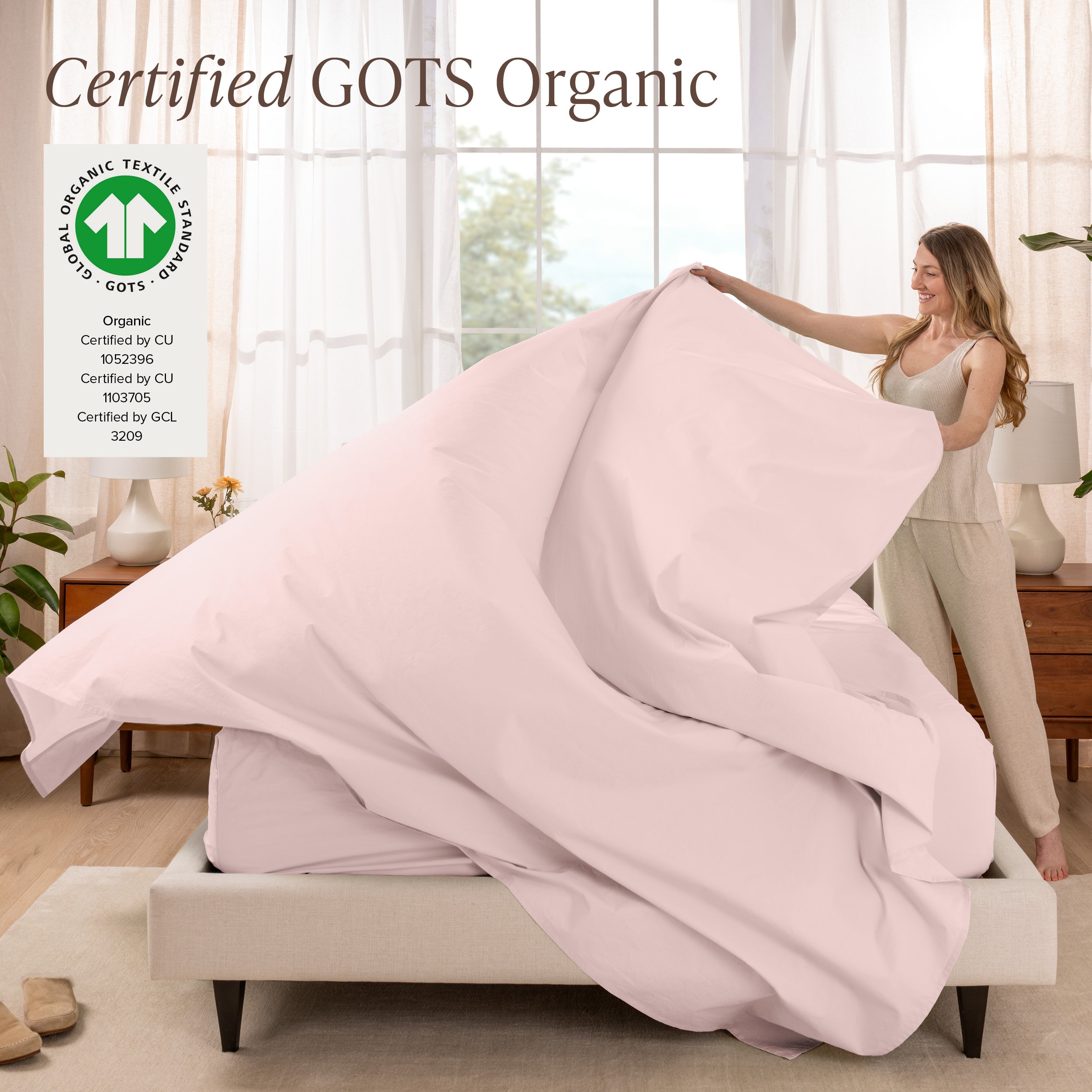 A woman is making a bed with organic cotton percale sheets