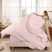 Woman putting a sheet set on a bed in a bright bedroom.