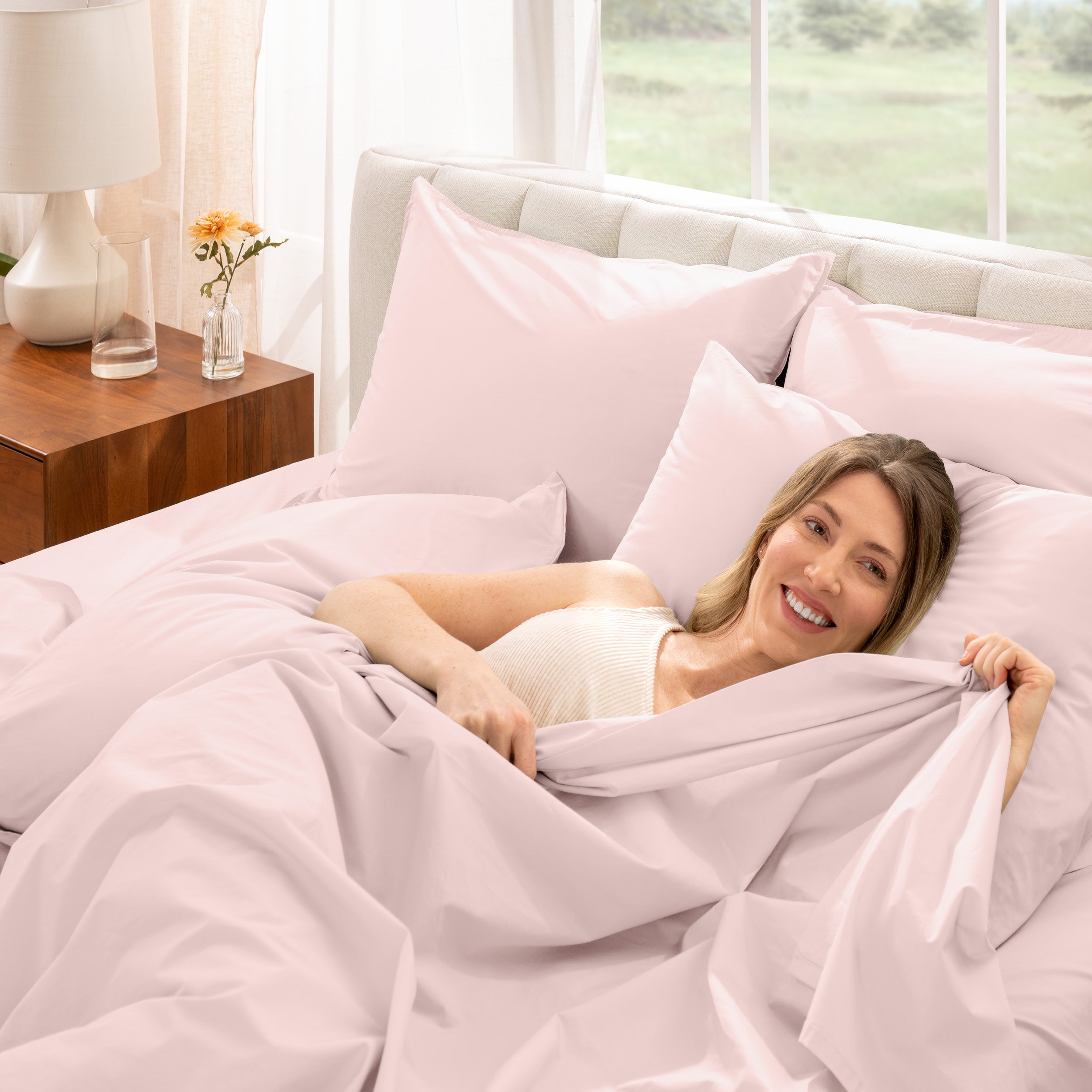 A woman is lying on a bed make with percale sheets and pillowcases